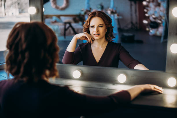 istock Beautiful redhead women looking in mirror at herself 1217576385