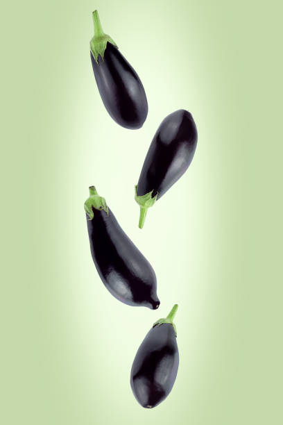 istock Falling eggplants isolated on green background with clipping path. Flying food. 1217578498