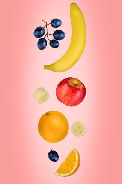 istock Falling apples, bananas, oranges, and grapes isolated on a pink background with clipping path. Flying food. 1217578504