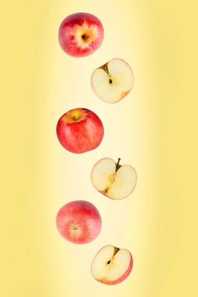 istock Falling red apples isolated on a yellow background with clipping path. Flying food 1217578509