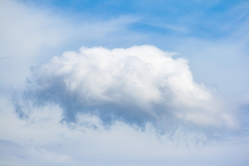 Large cloud formed in the sky surrounded by diffuse clouds and a blue sky in the background
