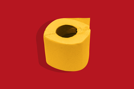 Papel higiénico amarillo sobre un fondo rojo. Rollo de papel sobre un fondo de color. photo