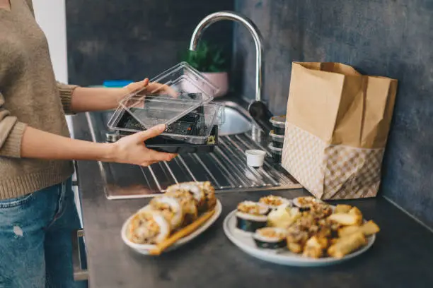 Woman recycling plastic containers after unpacking takeaway food delivery