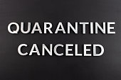 the words quarantine canceled laid with silver metal letters on matte back flat surface directly above in flat lay perspective