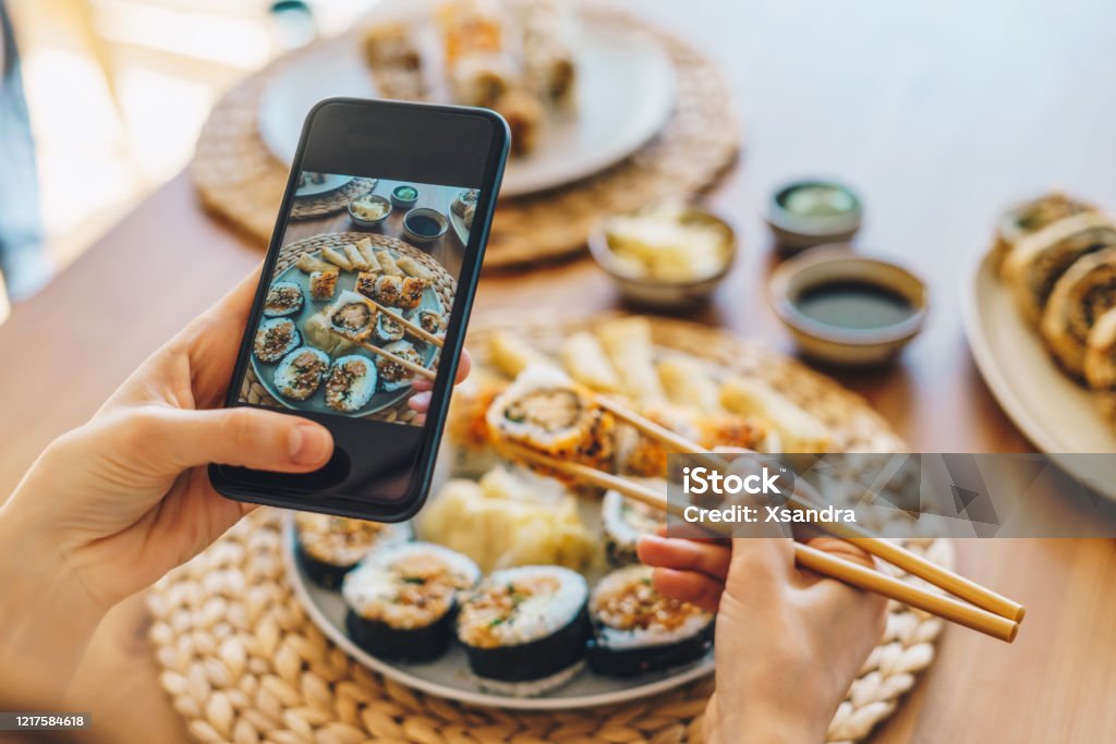 Mujer tomando foto de sushi maki con smartphone - Foto de stock de Sushi libre de derechos
