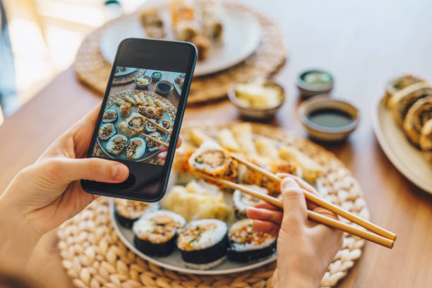 mujer tomando foto de sushi maki con smartphone - comida para llevar fotos fotografías e imágenes de stock