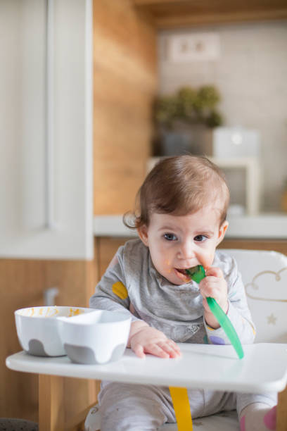 istock Baby eating by herself in high chair 1217585475