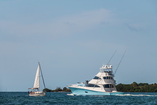 Sailboat and motor yacht approaching each other as they head in opposite directions along the Manatee River near Bradenton, Florida, USA, for nautical, recreational, and lifestyle themes