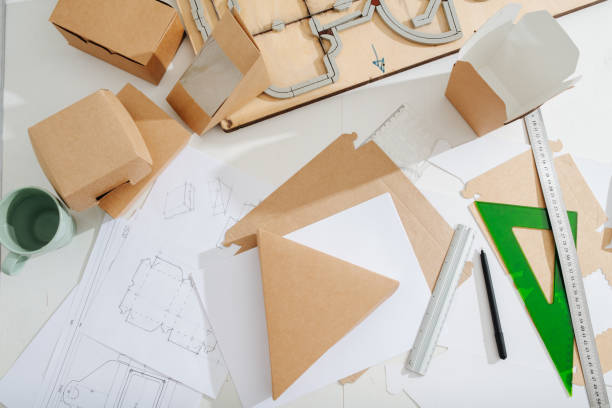 istock Workplace of a box maker, sheets, tools and scematics all across 1217589083