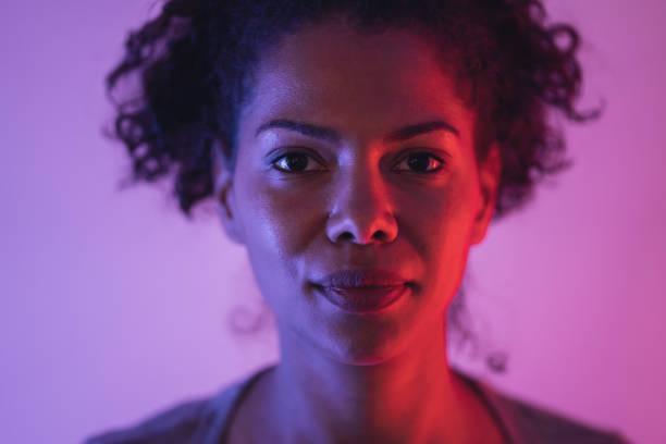 Portrait of woman A close-up portrait of a young afro-american woman lit by red and purple neon lights woman alone dark shadow stock pictures, royalty-free photos & images