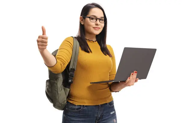Female student holding a laptop computer and showing thumbs up isolated on white background