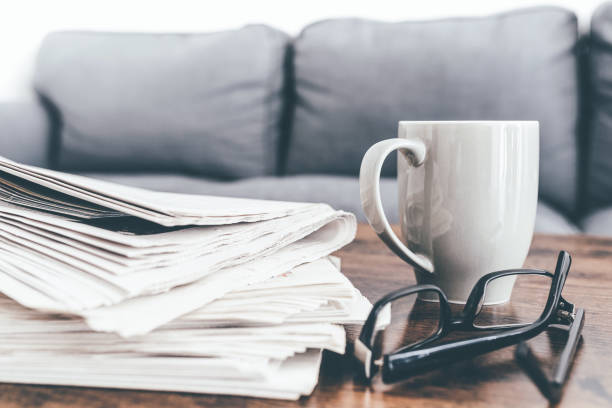 istock stack of newspapers, coffee mug and glasses on living room table 1217595545