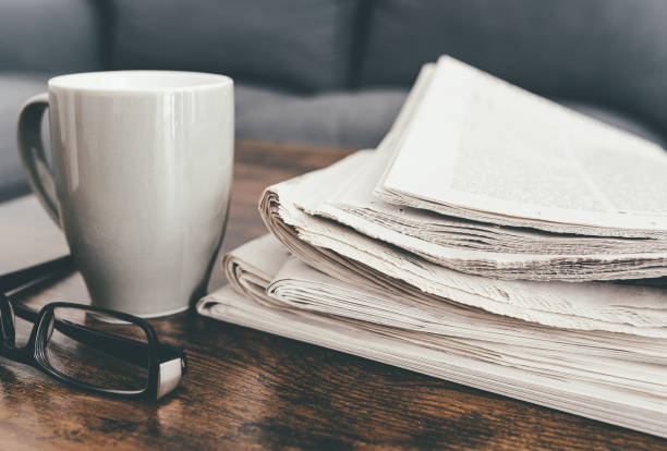 istock stack of newspapers, coffee mug and glasses on living room table 1217595709