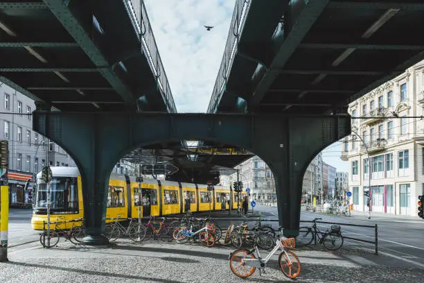 yellow street car passing intersection under metro bridge in Berlin Prenzlauer Berg
