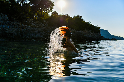 Woman throwing water in the sea with her hair.