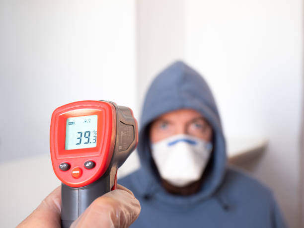 istock Taking a man's temperature with an infrared meter. High fever, symptom, disease. 1217600569