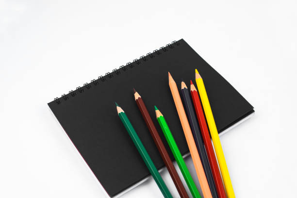 istock Different colored pencil crayons scattered on top of an isolated black paper diary 1217601178