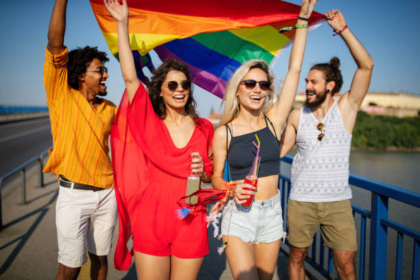 glückliche gruppe von menschen hängen in der stadt winken lgbt mit stolz flagge - pride lgbtqi veranstaltung stock-fotos und bilder