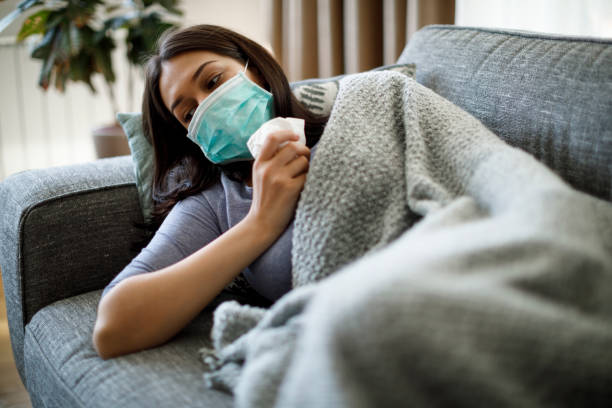 istock Sick woman with face protective mask lying in bed 1217604223