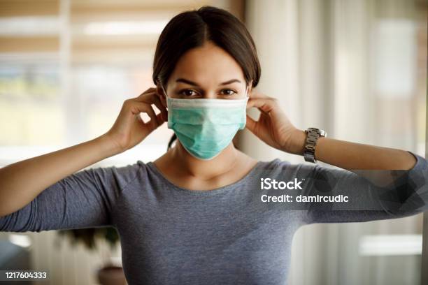 Portret Van Jonge Vrouw Die Op Een Beschermend Masker Voor Coronavirusisolatie Zet Stockfoto en meer beelden van Beschermend masker - Werkkleding