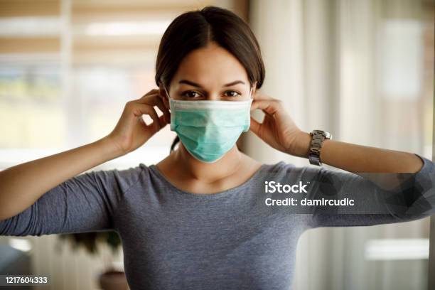 Portrait Of Young Woman Putting On A Protective Mask For Coronavirus Isolation Stock Photo - Download Image Now