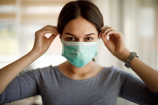 Portrait of young woman putting on a protective mask Portrait of young woman putting on a protective mask surgical mask stock pictures, royalty-free photos & images