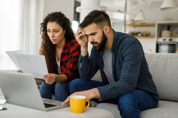 istock Young couple working on a budget while sitting on sofa in the living room 1217606894