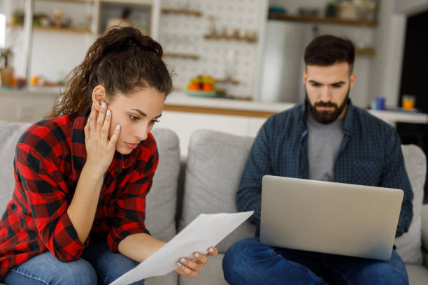 istock Young couple working on a budget while sitting on sofa in the living room 1217607756