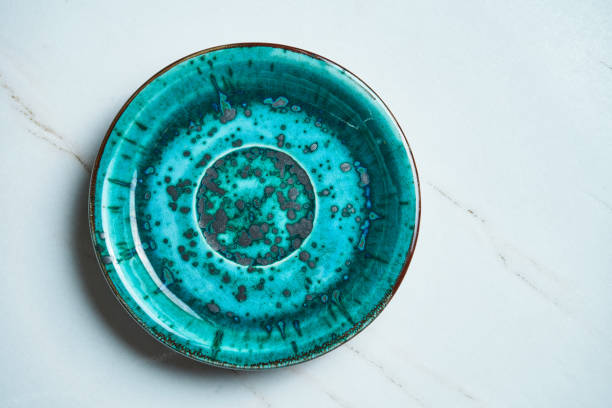 istock Top view on Handmade empty blue ceramic plate on a gray marble background. Copy space for text. Stylish kitchen utensils 1217607764