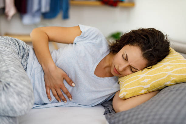 istock Young woman suffering from abdominal pain while lying down on bed at home 1217607962