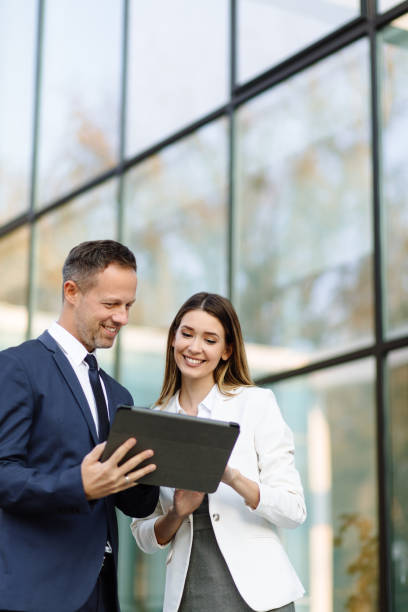 istock Two business people discussing work on tablet computer outdoors 1217609282