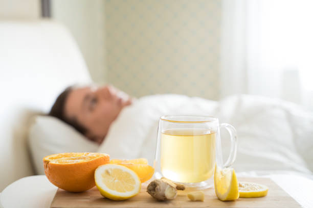 Cup with antipyretic drugs for colds,flu.Sick man in bed. Tea with citrus vitamin C,ginger root,lemon,orange.Wooden tray. Home self-treatment.Medical quarantine antiviral covid-19 coronavirus therapy. taza con medicamentos antipiréticos para resfriados, gripe. enfermo en la cama. té con vitamina c cítrica, raíz de jengibre, limón, naranja. bandeja de madera. autotratamiento en el hogar. terapia médica de cuarentena antiviral cóvido-19 coronavirus