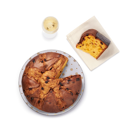 Panettone with cut slice and glass of sparkling wine, isolated on white background, top view.