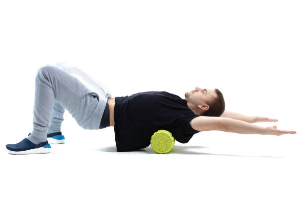 un homme fait des exercices de renforcement pour le corps avec des équipements sportifs spéciaux. auto-massage boostant le ton du corps - massage ball photos et images de collection