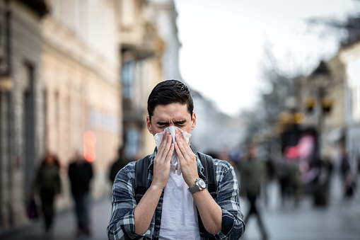 Man uses tissue paper sneezing due to having pollen allergy