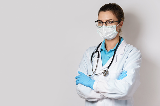Young female doctor with a stethoscope on grey background