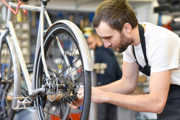 istock friendly and competent bicycle mechanic in a workshop repairs a bike 1217614383
