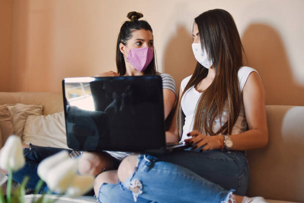 istock Two women with protective masks at home 1217616047