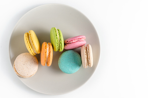 Macaroons of different colors on a plate on a white background