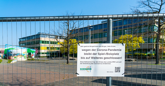 Bornheim, North Rhine-Westphalia, Germany - April 7, 2020: Local European School (Europaschule) closed due to global corona virus, COVID-19 pandemic. Education institution closure. Signboard with German text reading: „Schoolyard closed, because of corona virus“.