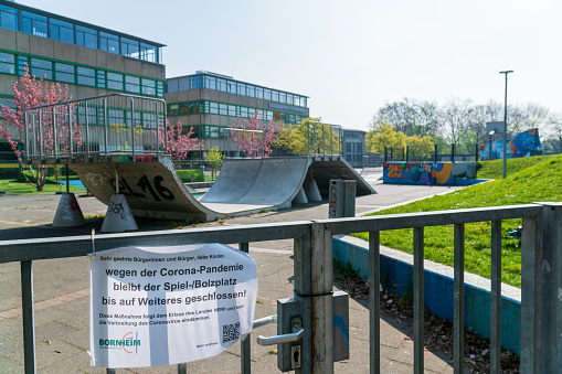 Bornheim, North Rhine-Westphalia, Germany - April 7, 2020: Local European School (Europaschule) with skate park closed due to global corona virus, COVID-19 pandemic. Education institution closure. Signboard with German text reading: „Schoolyard closed, because of corona virus“.