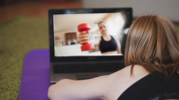 istock Young women exercising at home with online help on laptop 1217626200