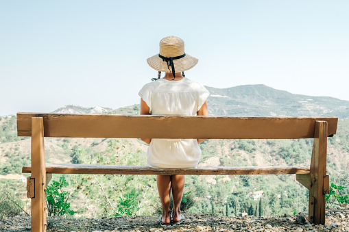 Beautiful woman wearing straw hat looking out towards valley view