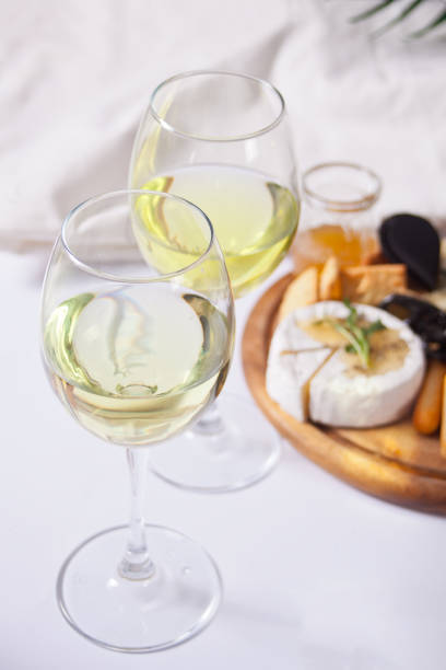 istock Two glasses of white wine and plate with assorted cheese, fruit and other snacks for party 1217628309