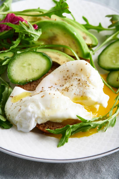istock Poached eggs with herbs, avocado and cucumber served on a plate on a light background Copy space 1217631218
