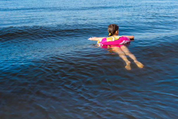 istock Child floating with an inflatable lap on the sea won.  Back view. 1217631354