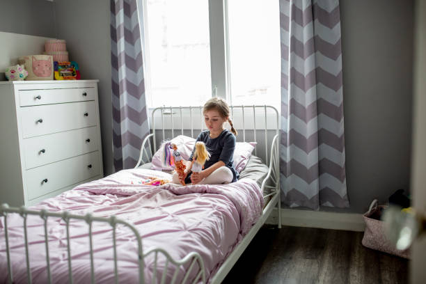 Cute young child plays with dolls in her bedroom.