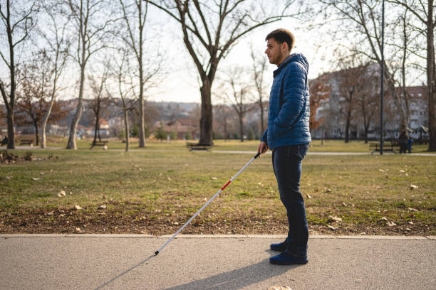 istock Young visually impaired man with walking cane checking if there is any obstacle on his way 1217635354