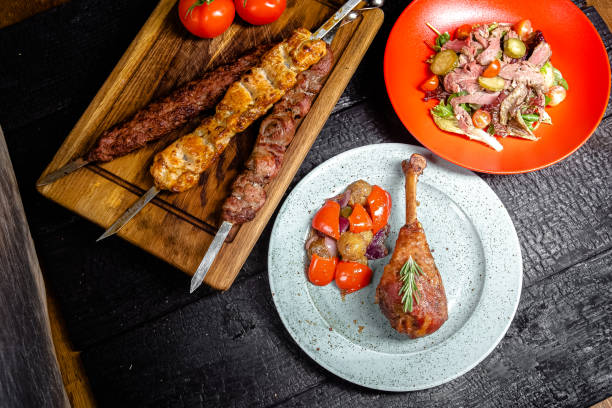 istock background black burnt carbonized forest, structure, wooden cutting board, turkey drumstick on a plate, skewers of different meat, grilled vegetables and fresh on a red plate 1217635384