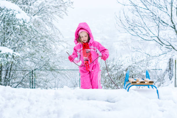 Mother and daughter enjoying sledge ride in snowy park